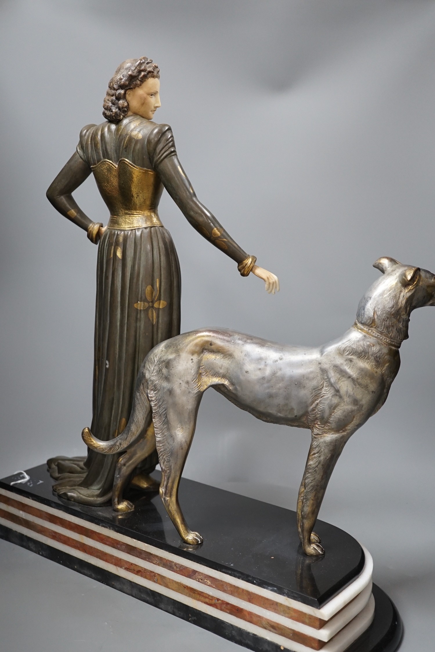 An Art Deco spelter and composition figure of a lady and a hound, signed Menneville, 57 cms high